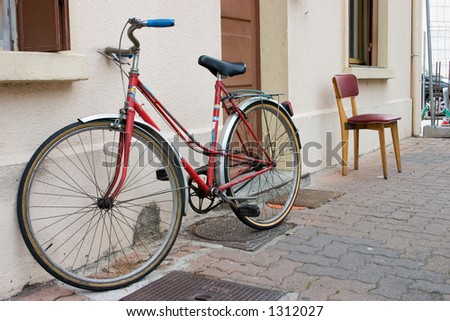 A bicycle and a chair next to a wall depicting the choice of rest or exercise.