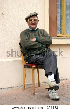 Sweet, elderly man sitting outside his apartment in a french village.
