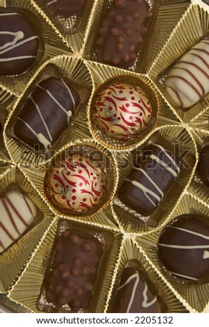 Closeup on a box of chocolates in gold colored tray.