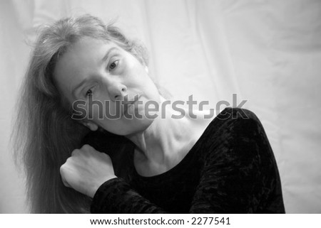 Middleaged woman without makeup in deep thought while brushing her hair.