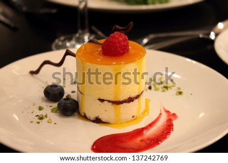 Delicious Mango Mousse Cake topped with raspberries and chocolate