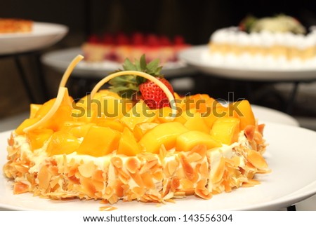 A Mango cake decorated with almonds and trawberry