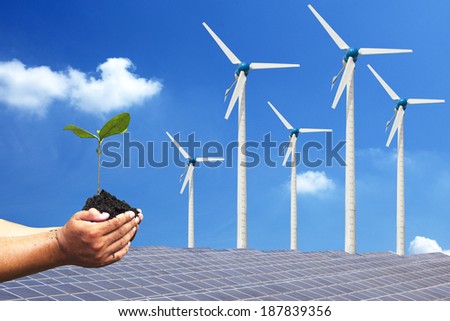 Hand holding seedling background solar cells and wind turbines. natural Energy