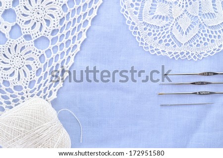 Crochet set. Crochet thread, doily and hooks on light blue linen fabric. Copy space.