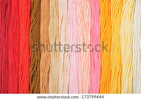 Colorful embroidery threads in a row. Warm colors background.