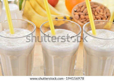 Banana and almond milk smoothie in a glass on a kitchen table. Summer drink made of banana, almond milk and few dactyl.