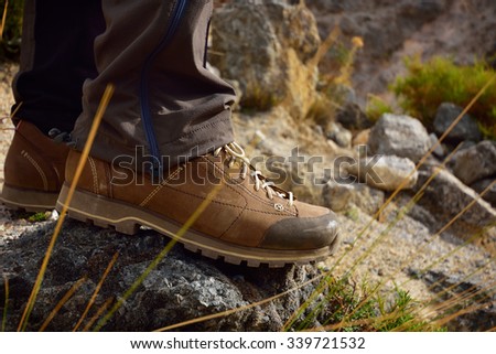 Outdoor hiking shoes in terrain. Men\'s legs feet in mountains. Hiker on Mountain trail path.