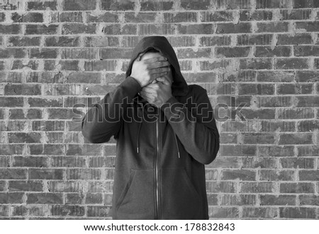 Young man covers his eyes and mouth with hands ,black and white