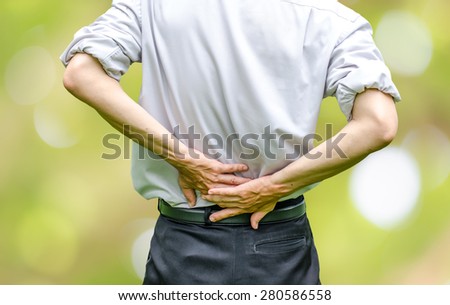 close up of a  man holding his back in pain