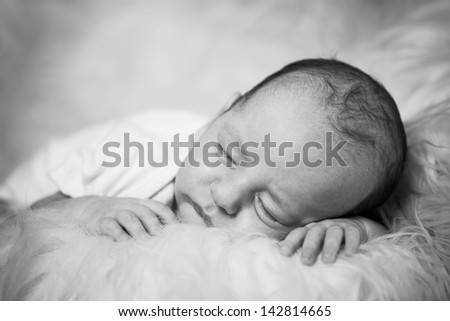 newborn baby boy sleeping on a soft sheep skins carpet