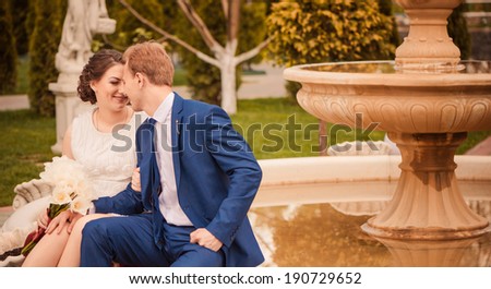 young lovely wedding couple at spring garden fountain