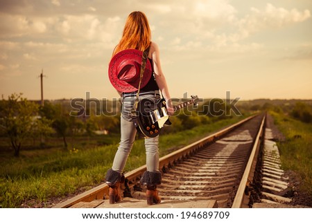 woman with guitar at railway trucks