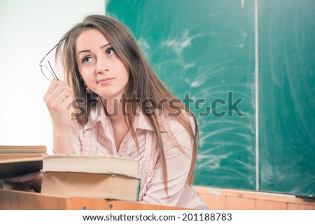 young woman teacher thinking at class blackboard