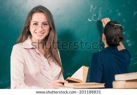 happy teacher portrait with student writing at blackboard