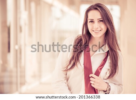 young smiling woman in white shirt and red tie at sunset business center background