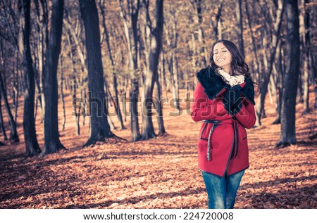 pretty young woman in red coat at fall fall forest