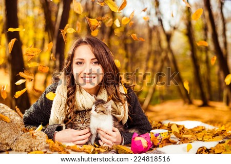 happy smiling woman with two cats under falling autumn leafs