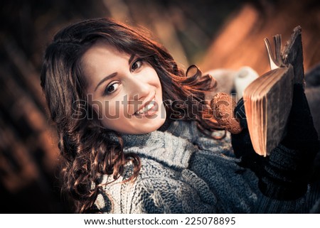 smiling woman with cookie and vintage book at fall season