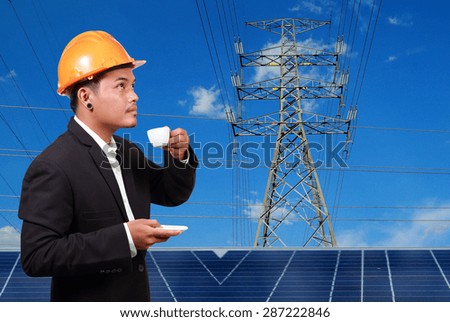 Engineer man with solar panel against high voltage towers background.