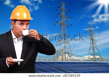 Engineer man with solar panel against high voltage towers background.