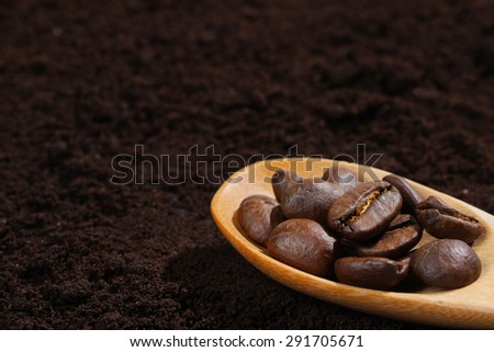 coffee beans in spoon on ground coffee