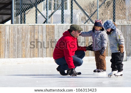 Family having fun at the outdoor skating rink in winter.