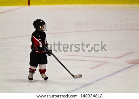 Child skating and playing hockey in an arena