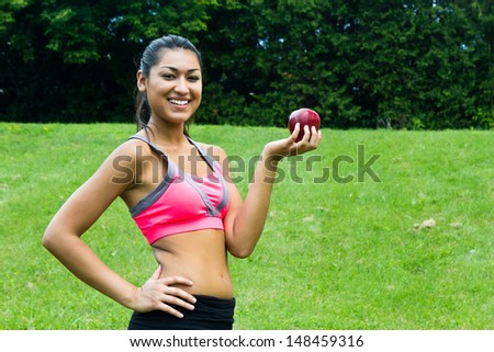 Fit young woman with an apple in the park