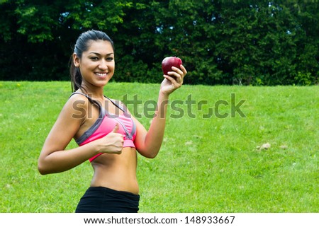 Fit young woman with an apple in the park