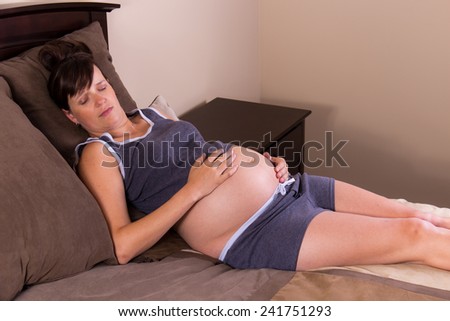 Pregnant woman taking a nap on her bed