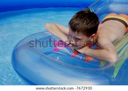 Boy on air-bed in swimming pool.