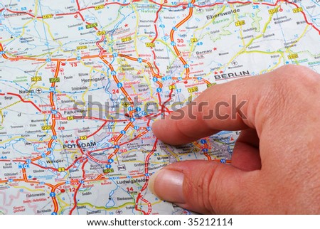 Close up of a hand pointing out Berlin on the map.