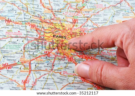 Close up of a hand pointing out Paris on a map.
