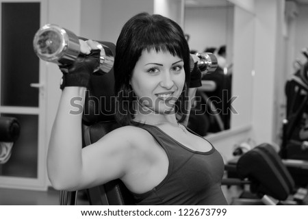 She performs bench dumbbell sitting on a bench in the Gym