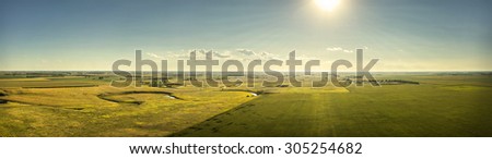 An aerial view from 300 feet above ground of a creek and landscape looking towards the sun.