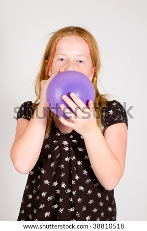 girl is blowing up a balloon on white