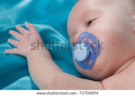 a sweet baby sleeping on a blue satin sheet