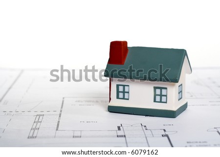 Real Estate Concept with Miniature Home atop blueprints.
