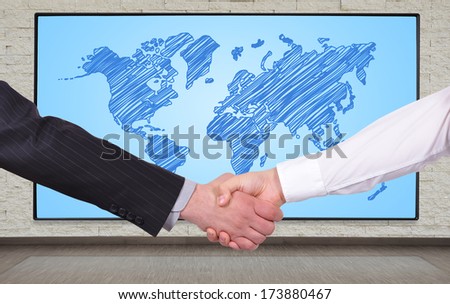 handshake on a big plasma panel with world map background