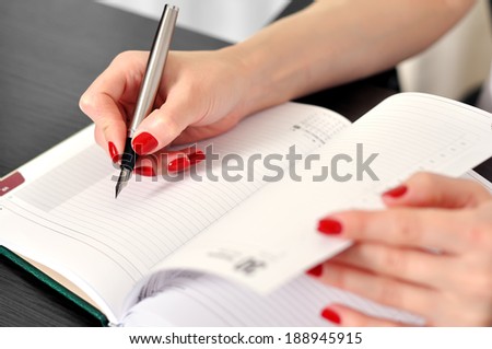 hand with fountain pen writing or signing on a blank diary