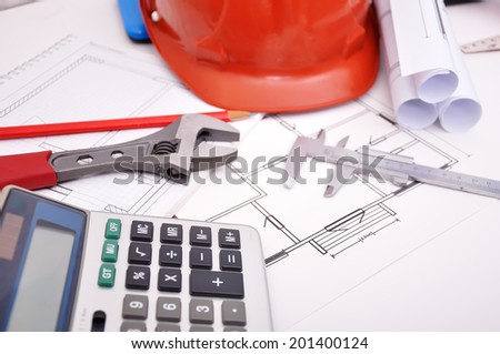 Calculator, helmet and drafting tools on architectural table