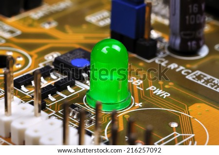 Green LED on yellow circuit board, close up