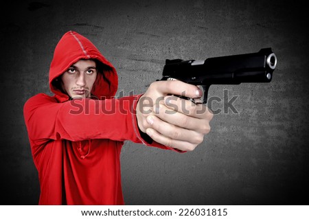 young burglar with gun in hand on a black background