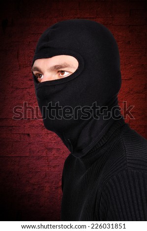 robber in mask on a green wall background