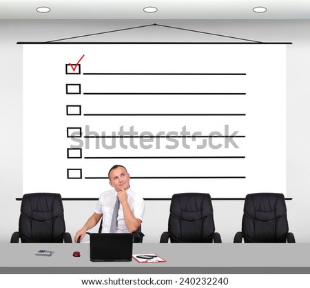businessman sitting in office and drawing check box on poster