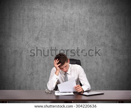 Tired businessman sitting in office and counts losses