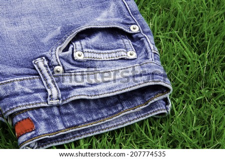 Jeans background with a green grass.