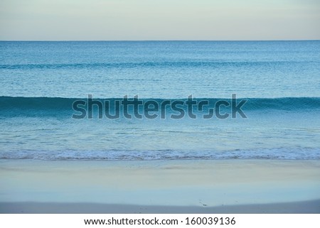 lines of small waves rolling in to fine sandy beach
