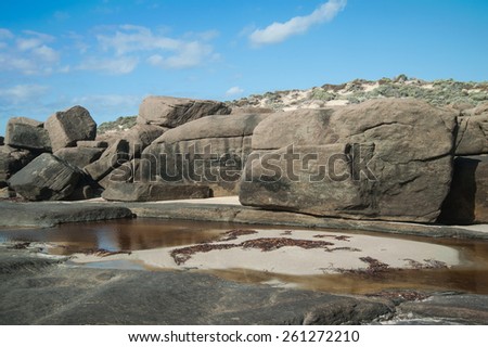 Large granite rocks on coast with sandhill partly covered in low scrub behind and tidal pool in front, at Injidup Point SW Western Australia