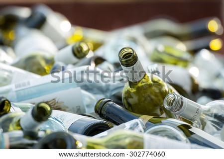 Collection of empty wine bottles of various colours piled in disorder in bin